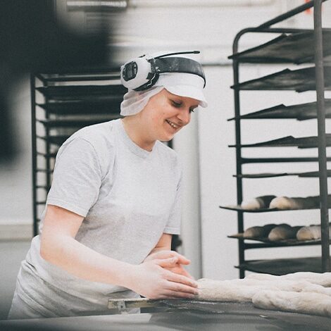 Leipuri leipoo gluteenitonta leipää leipomossa työvaatteissa